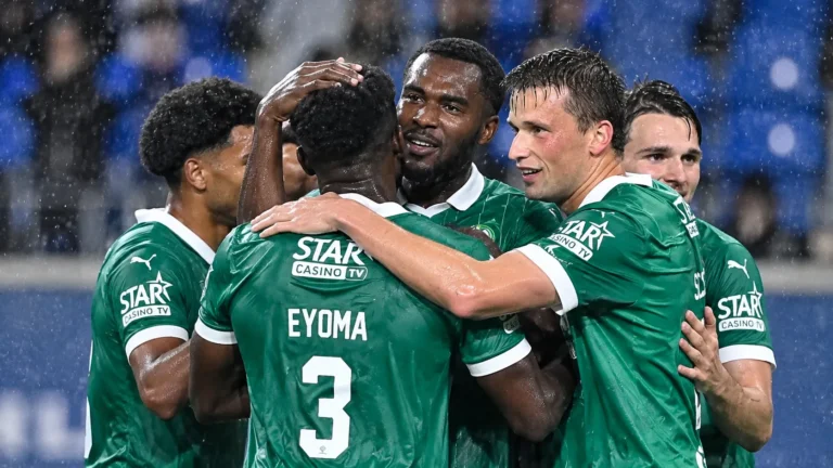 Een groep Lommel-spelers viert samen in de regen op het veld.