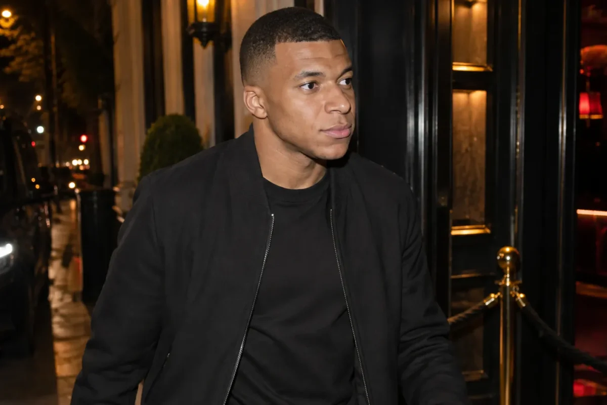 Kylian Mbappé bij de ingang van een Parijse nachtclub in neutrale burgerkleding.