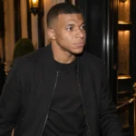 Kylian Mbappé bij de ingang van een Parijse nachtclub in neutrale burgerkleding.
