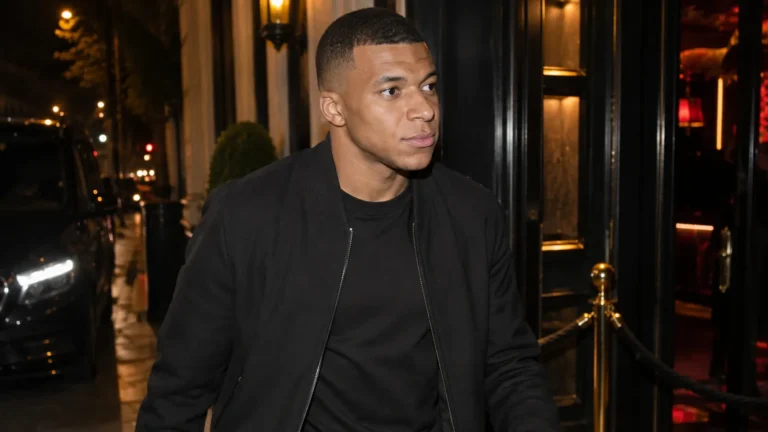Kylian Mbappé bij de ingang van een Parijse nachtclub in neutrale burgerkleding.