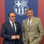 Twee mannen in pak bij een clubachtergrond van FC Barcelona.