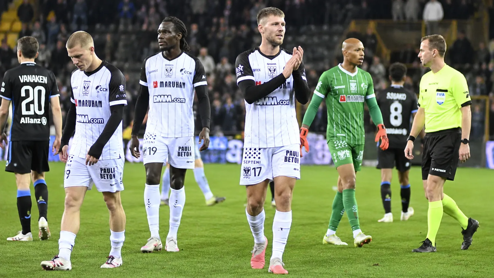 Spelers en een scheidsrechter op het veld na het laatste fluitsignaal.