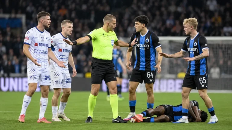 Een scheidsrechter staat tussen spelers na het laatste fluitsignaal van Club Brugge tegen STVV.