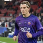 Een PSG-speler in een paars trainingsshirt op het veld voor een wedstrijd.