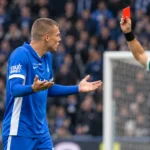 Daan Heymans van KRC Genk reageert terwijl een scheidsrechter een rode kaart toont.