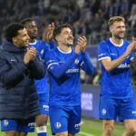 Een groep KAA Gent-spelers applaudisseert op het veld na een thuiswedstrijd.