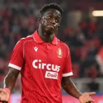 Een voetballer in een rood shirt reageert na een wedstrijd op het veld.