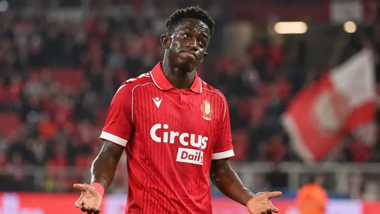 Een voetballer in een rood shirt reageert na een wedstrijd op het veld.