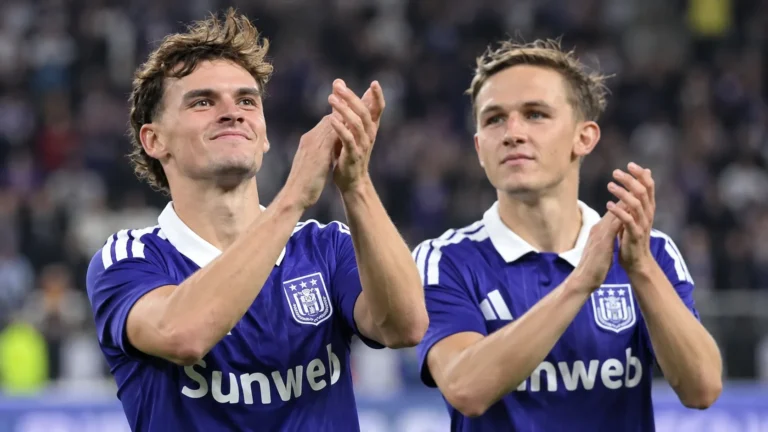 Twee spelers van Anderlecht applaudisseren na een wedstrijd in paarse shirts.
