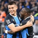 Twee voetballers in zwart-blauwe shirts vieren samen na een wedstrijd.