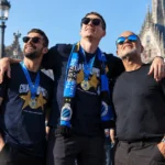 Een groep Club Brugge-supporters met blauw-zwarte sjaals op een stadsplein.
