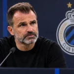Een Club Brugge-coach in zwarte trui tijdens een rustig moment in de mediaruimte.