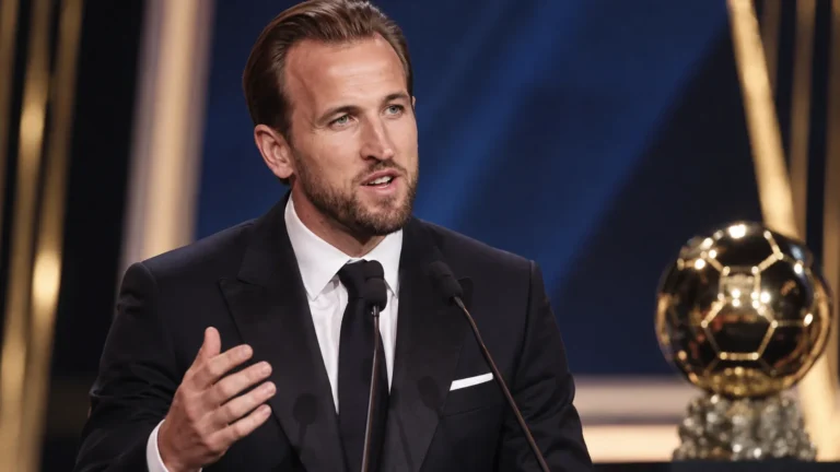 Harry Kane spreekt in een donker pak op het podium van de Gouden Bal.