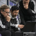 Technische staf van Anderlecht aan de dug-out met een laptop tijdens een wedstrijd.