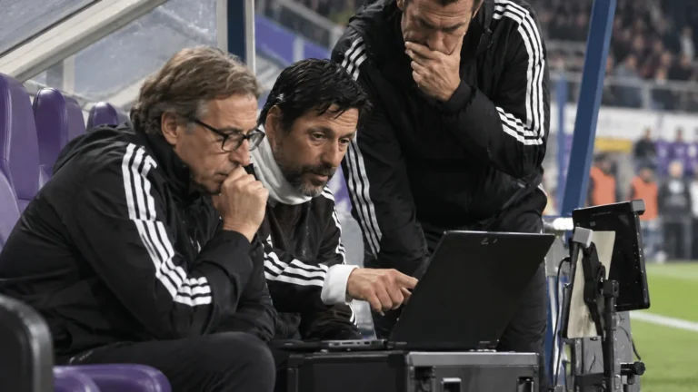 Technische staf van Anderlecht aan de dug-out met een laptop tijdens een wedstrijd.