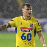 Normas Bassette in het geel-blauwe shirt van Westerlo op een regenachtig veld.