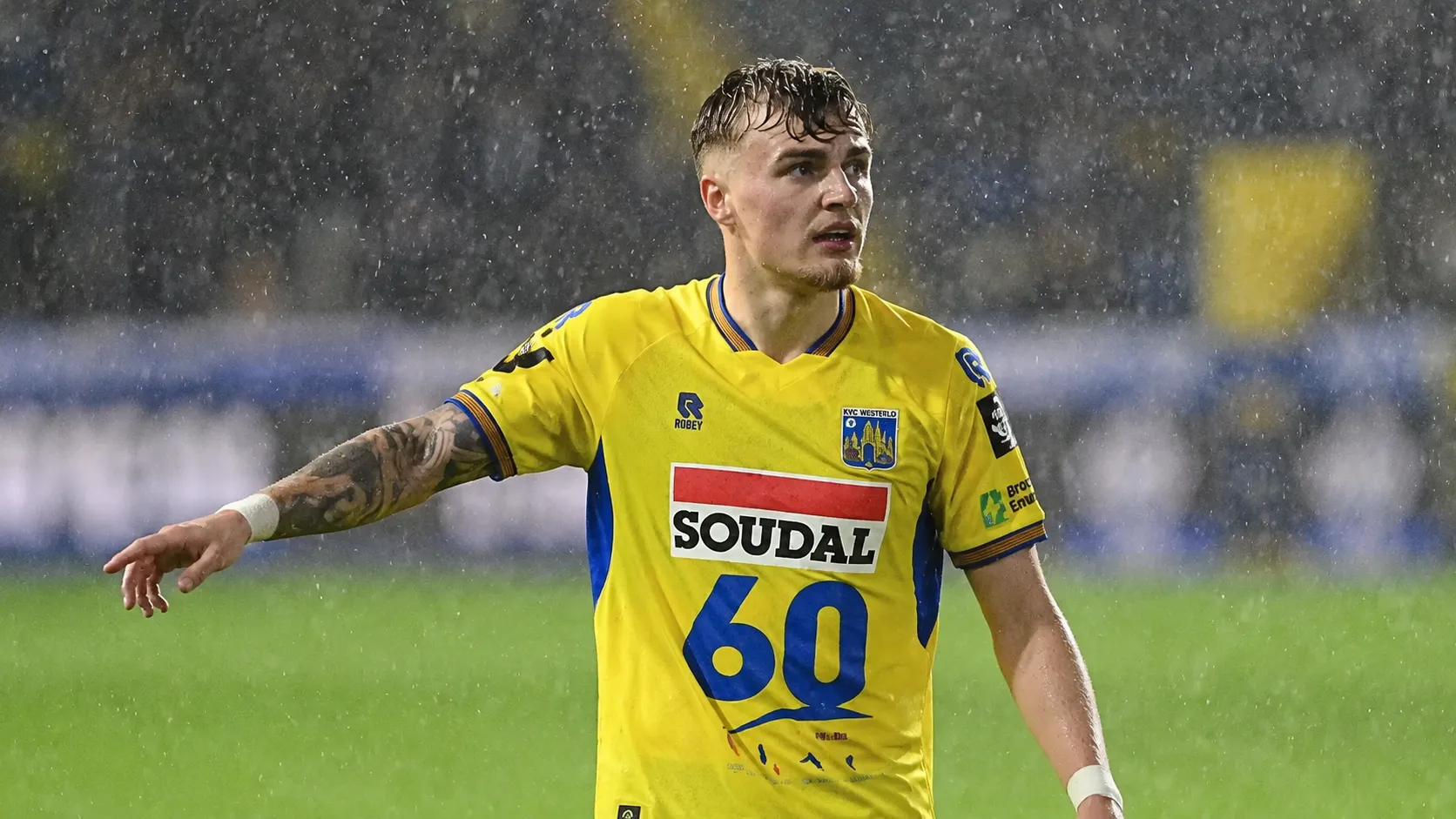 Normas Bassette in het geel-blauwe shirt van Westerlo op een regenachtig veld.