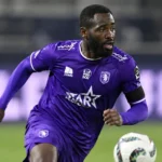 Arnold Vula in paars wedstrijdtenue tijdens een aanvallende actie op het voetbalveld.