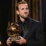 Harry Kane houdt de Ballon d'Or vast op een verlicht prijzenpodium.