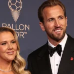 Een man en vrouw in avondkleding voor een achtergrond van een voetbalprijsuitreiking.
