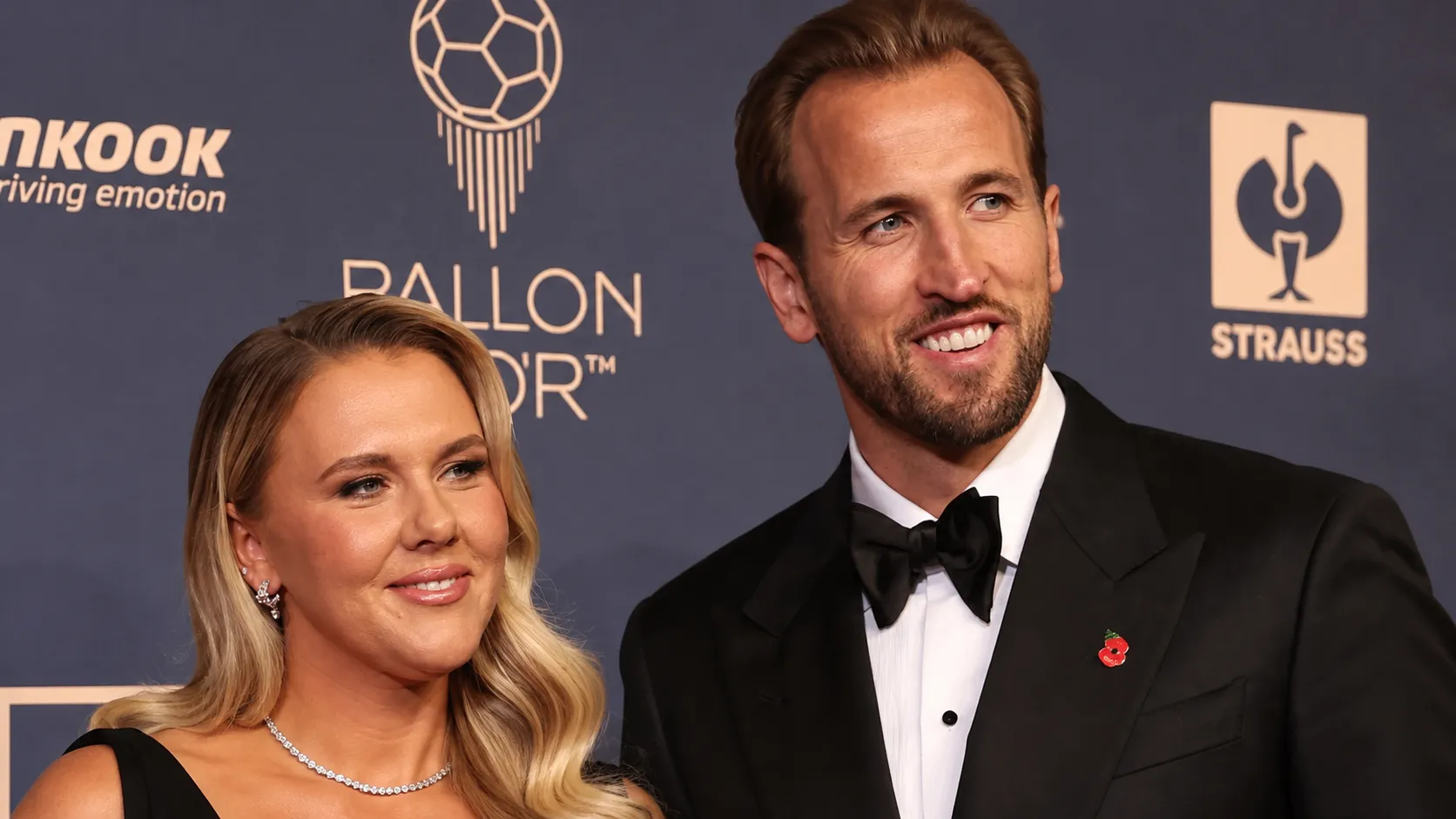 Een man en vrouw in avondkleding voor een achtergrond van een voetbalprijsuitreiking.