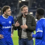 KAA Gent-spelers en een staflid staan samen aan de rand van het veld.
