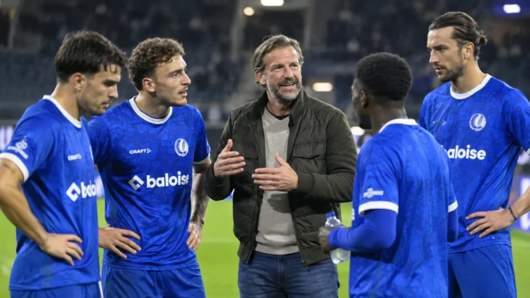 KAA Gent-spelers en een staflid staan samen aan de rand van het veld.