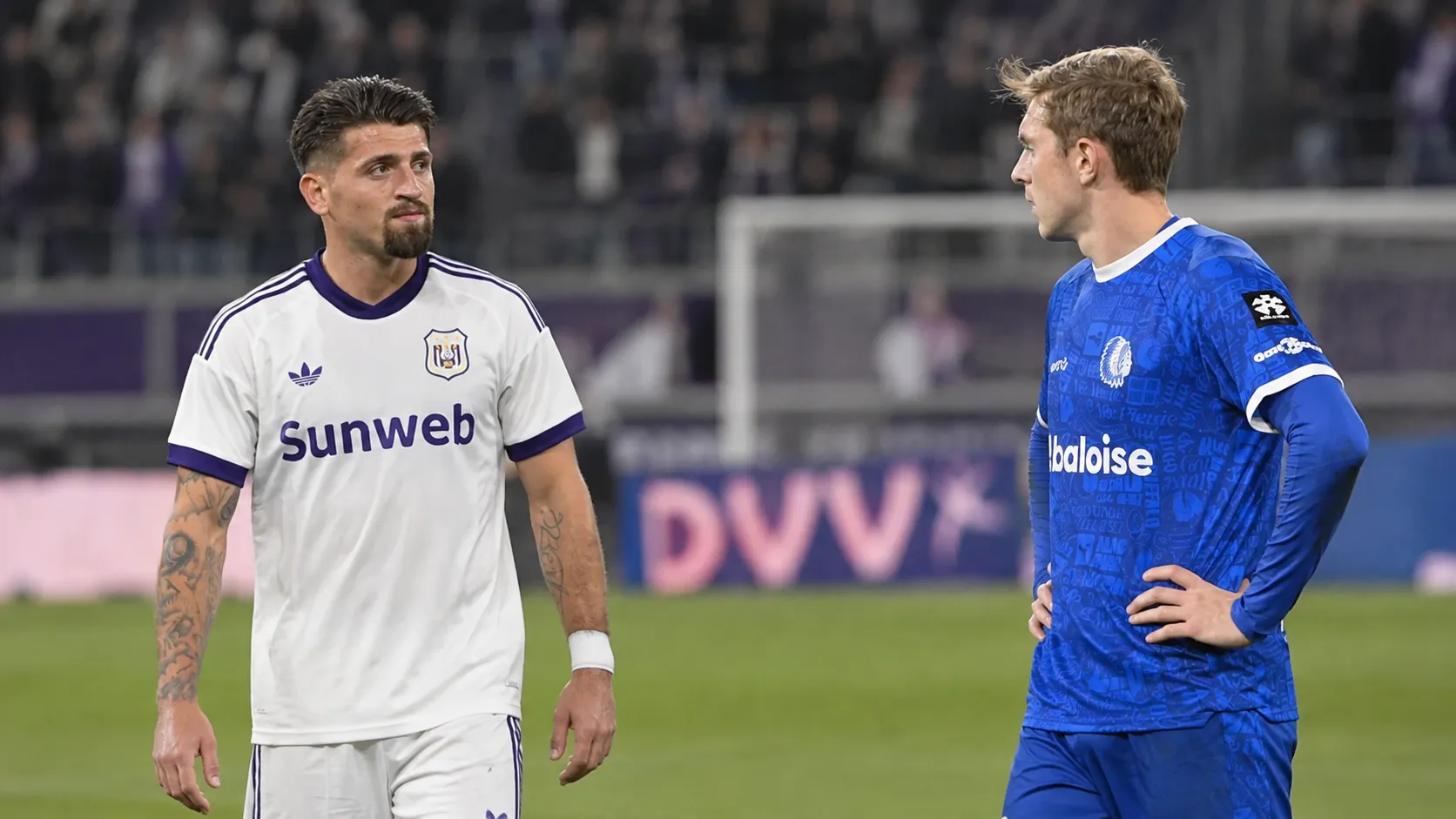 Twee voetballers van de tegenstanders praten na afloop op het veld.