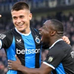 Twee spelers van Club Brugge vieren samen een doelpunt op het veld.