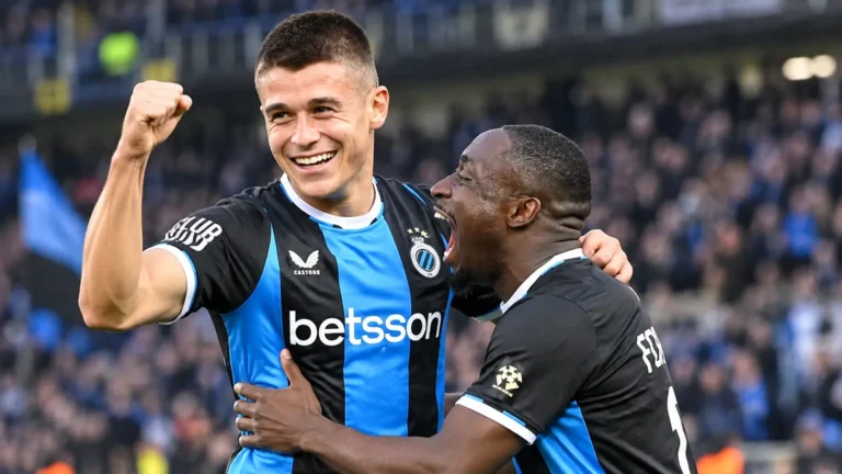 Twee spelers van Club Brugge vieren samen een doelpunt op het veld.