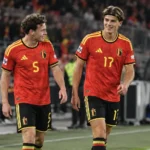 Twee Belgische internationals in rode shirts staan na een spelmoment aan de zijlijn.