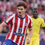 Een speler van Atlético Madrid in een rood-wit gestreept shirt tijdens een wedstrijd.