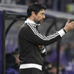 Vítor Bruno staat langs de zijlijn naast een paars dugoutpaneel van RSC Anderlecht.