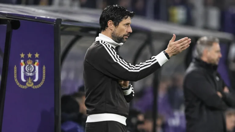 Vítor Bruno staat langs de zijlijn naast een paars dugoutpaneel van RSC Anderlecht.