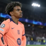 Lamine Yamal in het shirt van FC Barcelona langs de zijlijn van een verlicht stadion.