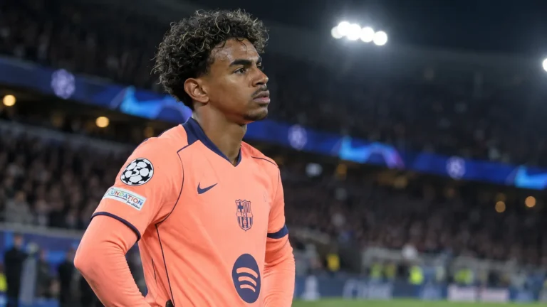 Lamine Yamal in het shirt van FC Barcelona langs de zijlijn van een verlicht stadion.