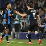 Twee Club Brugge-spelers in zwart-blauwe tenues bij de zijlijn tijdens een wedstrijd.