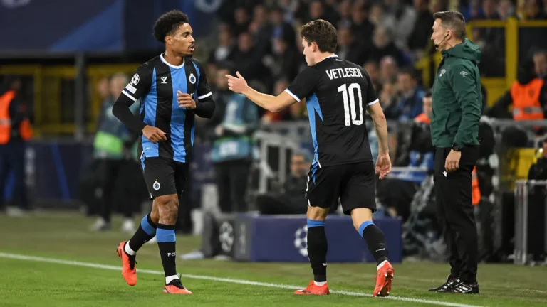 Twee Club Brugge-spelers in zwart-blauwe tenues bij de zijlijn tijdens een wedstrijd.