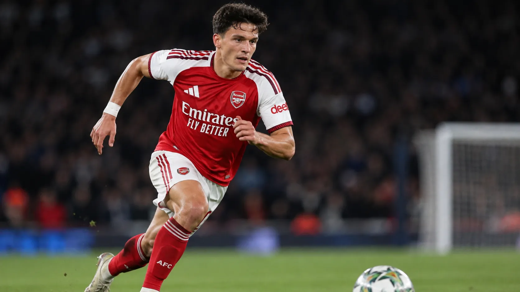 Een Arsenal-speler in het thuistenue jaagt tijdens een bekerwedstrijd op de bal.