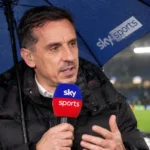 Gary Neville spreekt onder een paraplu in een Sky Sports-microfoon.