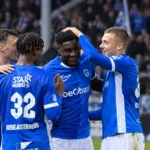 Een groep spelers van KRC Genk viert samen op het veld tijdens een wedstrijd.