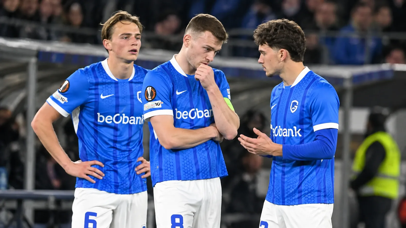 Drie spelers van KRC Genk tijdens een rustig moment langs het veld.
