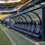 Lege technische zone langs het veld met een Fenerbahçe-embleem op het zijpaneel van de dug-out.