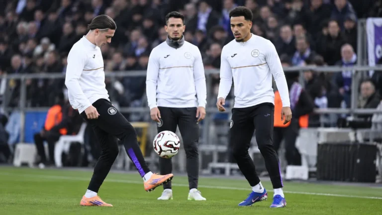 Een groep Anderlecht-spelers warmt op langs de zijlijn van een voetbalstadion.