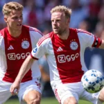 Twee voetballers in rood-witte shirts tijdens een wedstrijdmoment.