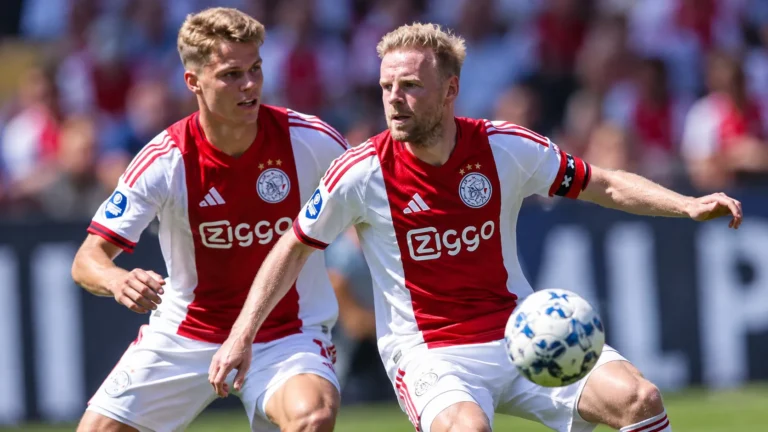 Twee voetballers in rood-witte shirts tijdens een wedstrijdmoment.