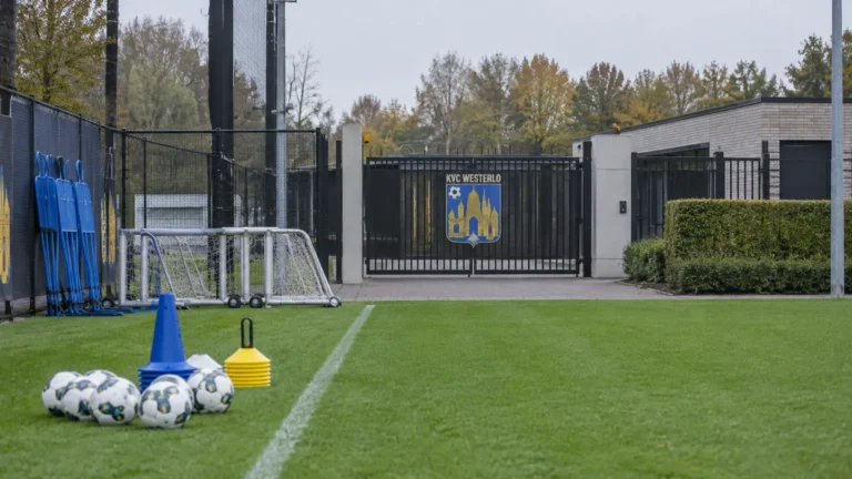 Lege oefenzone aan het trainingscomplex van KVC Westerlo met een clubembleem op de toegangspoort.