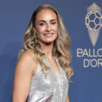 Tessa Wullaert in een zilveren avondjurk voor een blauwe Ballon d'Or-eventwand.