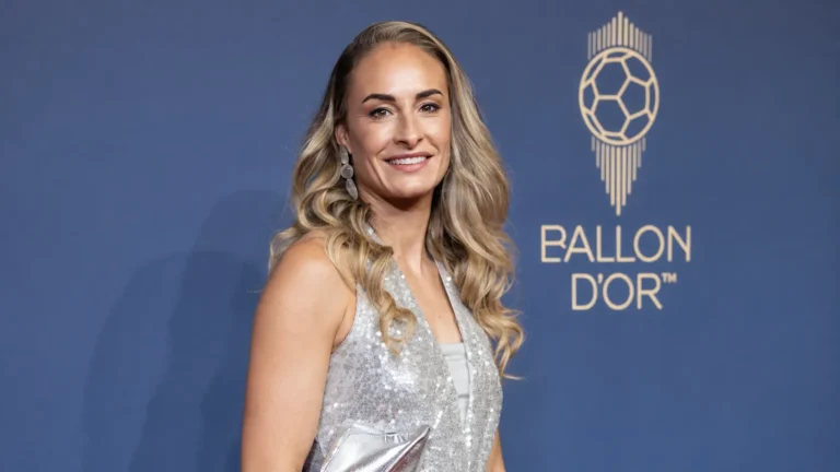 Tessa Wullaert in een zilveren avondjurk voor een blauwe Ballon d'Or-eventwand.