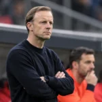 Een lid van de technische staf van Standard applaudisseert langs de zijlijn.